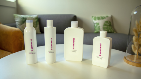 Four white Aptar e-commerce packaging bottles displayed on a table, showcasing multiple closure solutions for personal care products.