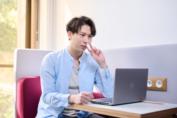 A man with a computer administering a single precise powder dose from an Aptar Unidose Powder Nasal Drug delivery system