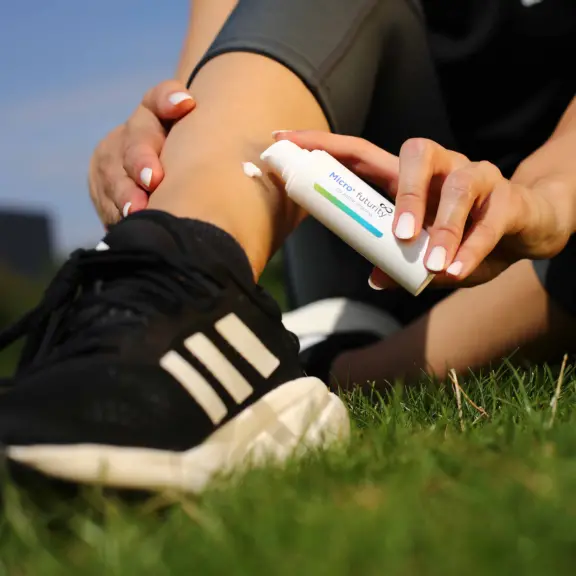 User applying a dermal formulation to the knee using an airless dispensing system for targeted topical or transdermal application.