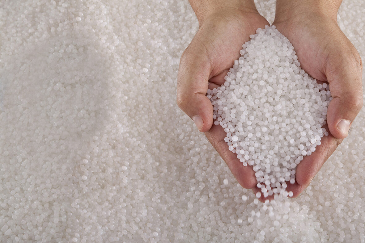 Two human hands holding small beads of recycled circular feedstock materials for APF futurity devices.